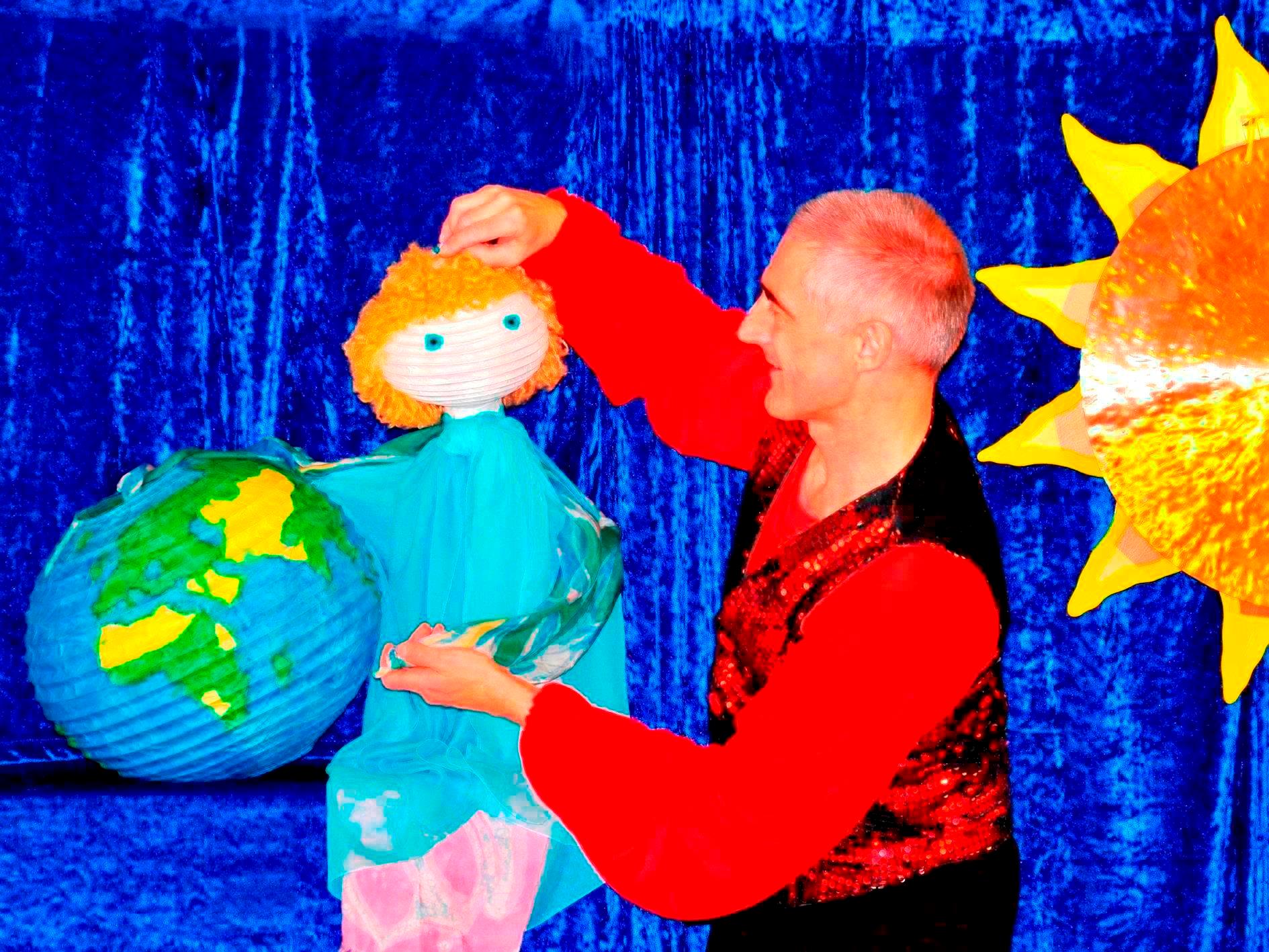 Puppenspieler mit Handpuppe vor blauem Vorhang