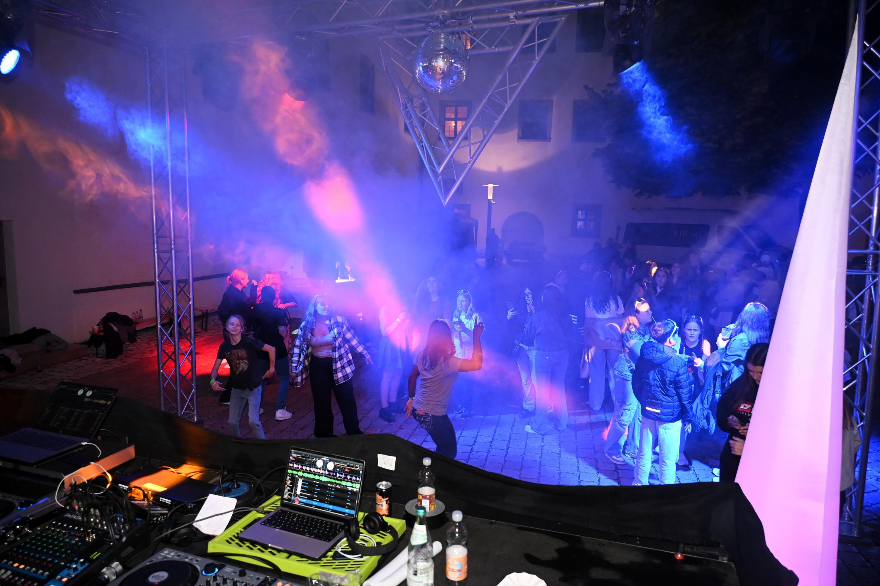 Tänzerinnen und Tänzer vor einer Bühne mit Discobeleuchtung
